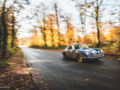 Porsche 911 F-model rijdt op een weg door het bos