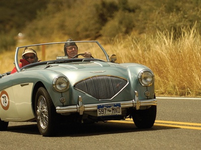 Austin Healy 100/4 met twee personen rijd op de weg