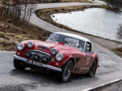 Austin Healey Trans rijd omhoog met een meer op de achtergrond